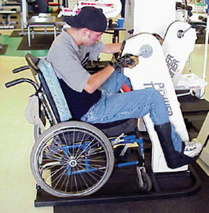 Man in a wheel chair using an upper body cycle at a fitness center