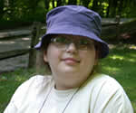 Smiling female camper with a blue denim hat and a yellow t-shirt.