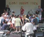 Several people standing facing a stage where a band is playing.