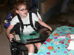 Female camper who uses a wheelchair approaching an activity table.