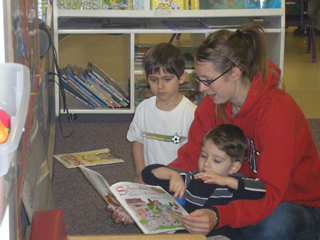 A woman reads a story to two young boys.