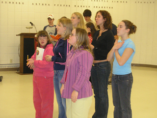 Female high school students both with and without disabilities sing together at play rehearsal.