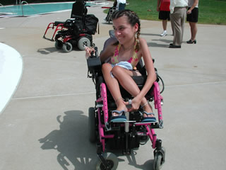 a teenage girl in a wheelchair sits by the pool